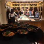 A lively indoor gathering with guests enjoying appetizers on a tray, set against a beautifully decorated kitchen backdrop.