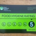 A sign displaying a food hygiene rating of 5, categorized as "Very Good," with a black and green design.